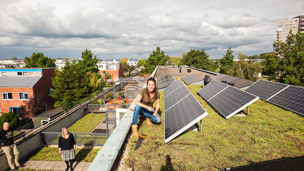 Een vrouw zit op een groen dak met zonnepanelen