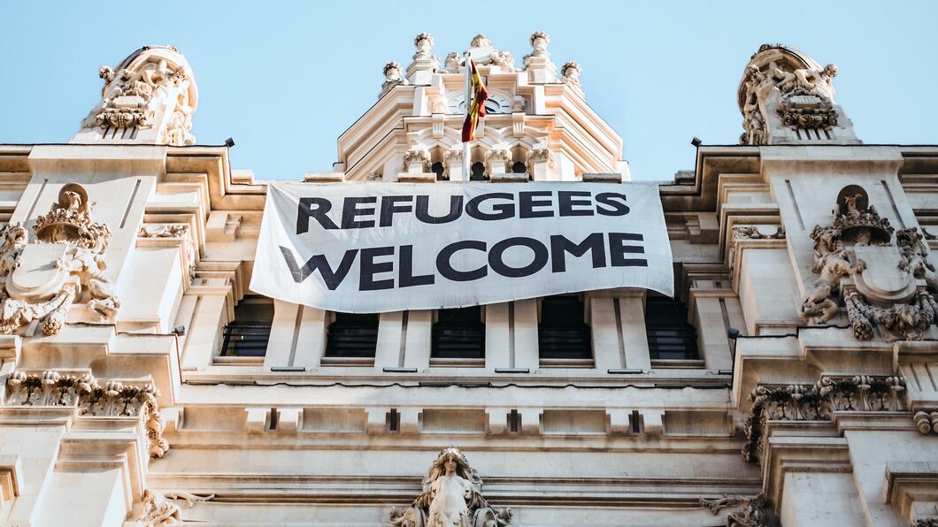 Een gebouw met een Refugees Welcome spandoek
