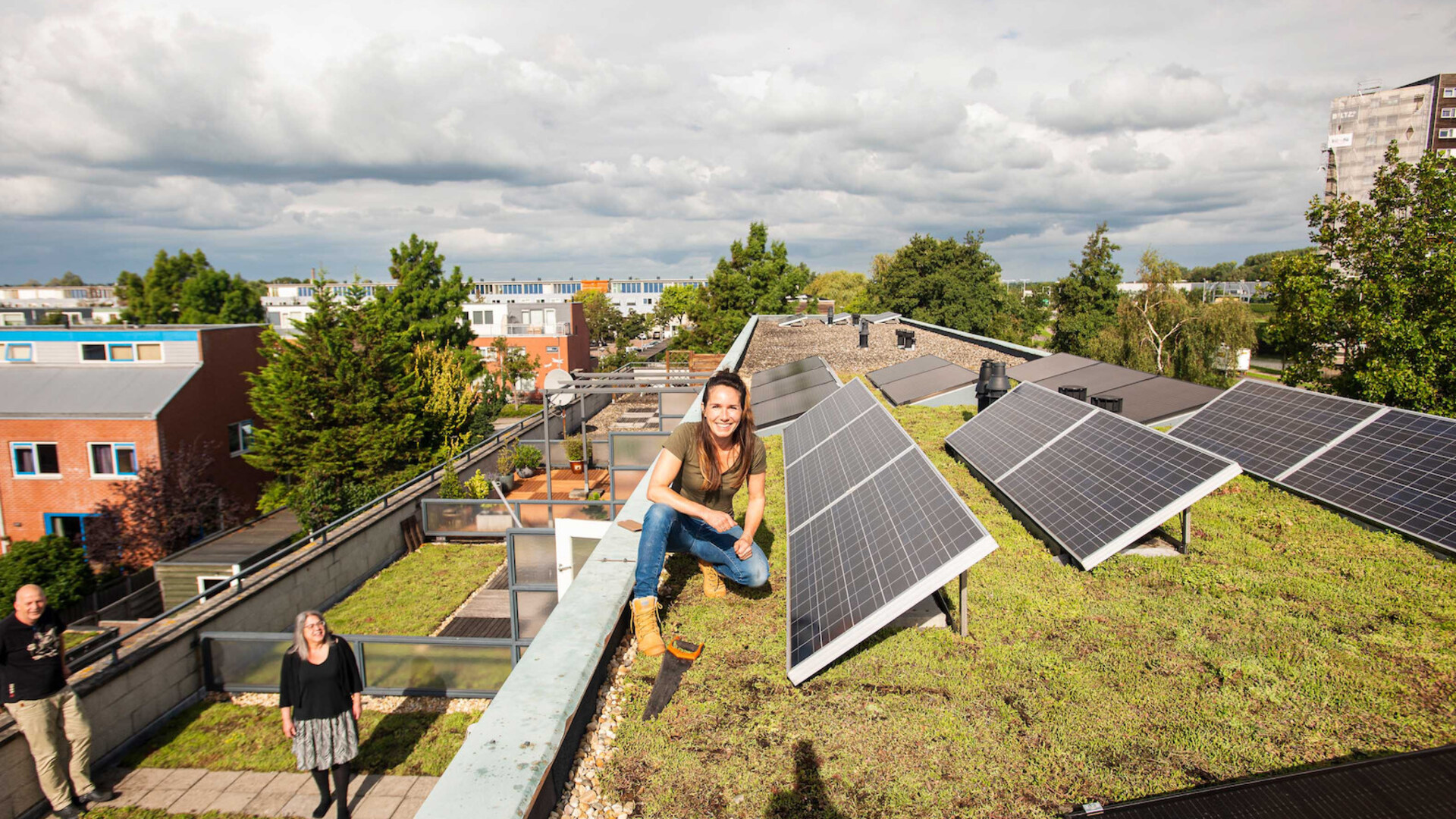 Een vrouw zit op een groen dak met zonnepanelen